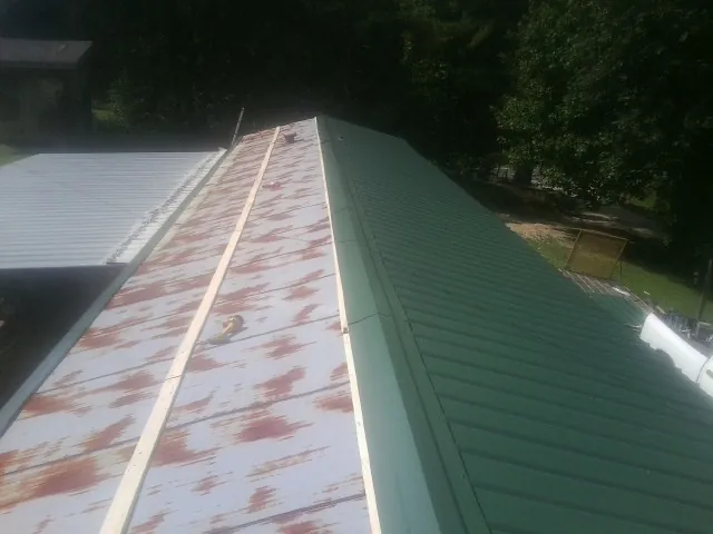 Old rusted panels beside newly installed green metal roofing — Wind Damage Roof Repair by Roofing Brothers in Cropwell