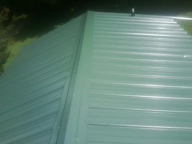 New green metal panels meeting at the ridge of a roof — Flat Roof Repair work by our crew in Cropwell