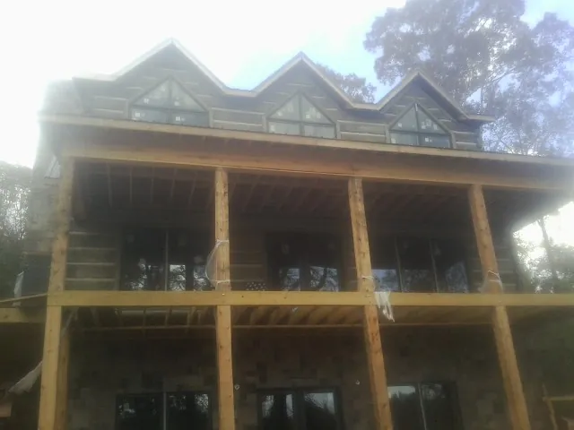 Dormers and porch framing on a large log home under construction — Roof Coating work by our crew in Cropwell