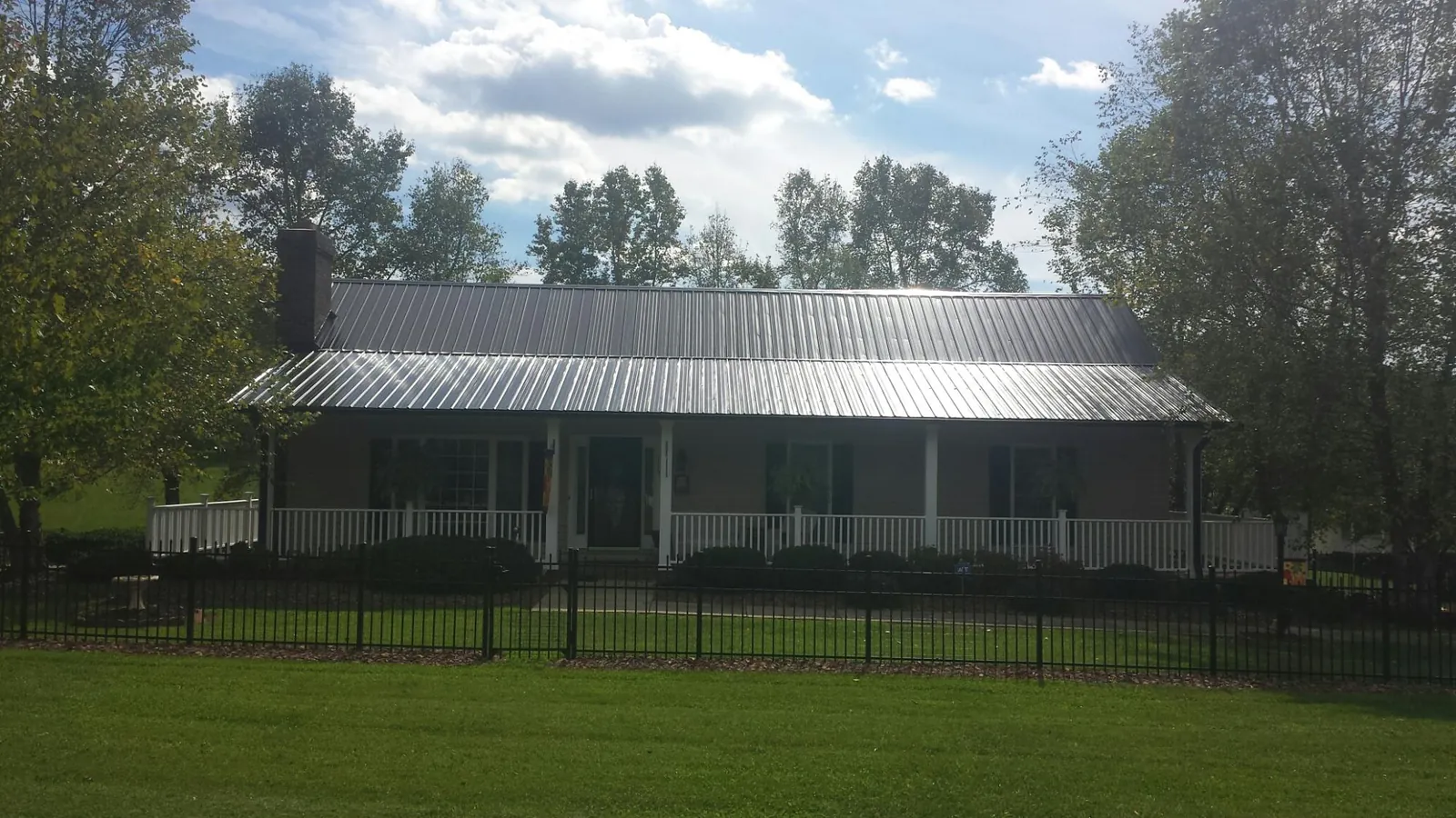Gray metal roof on a brick ranch with a full width front porch — Gutter Guard Installation work by our crew in Cropwell