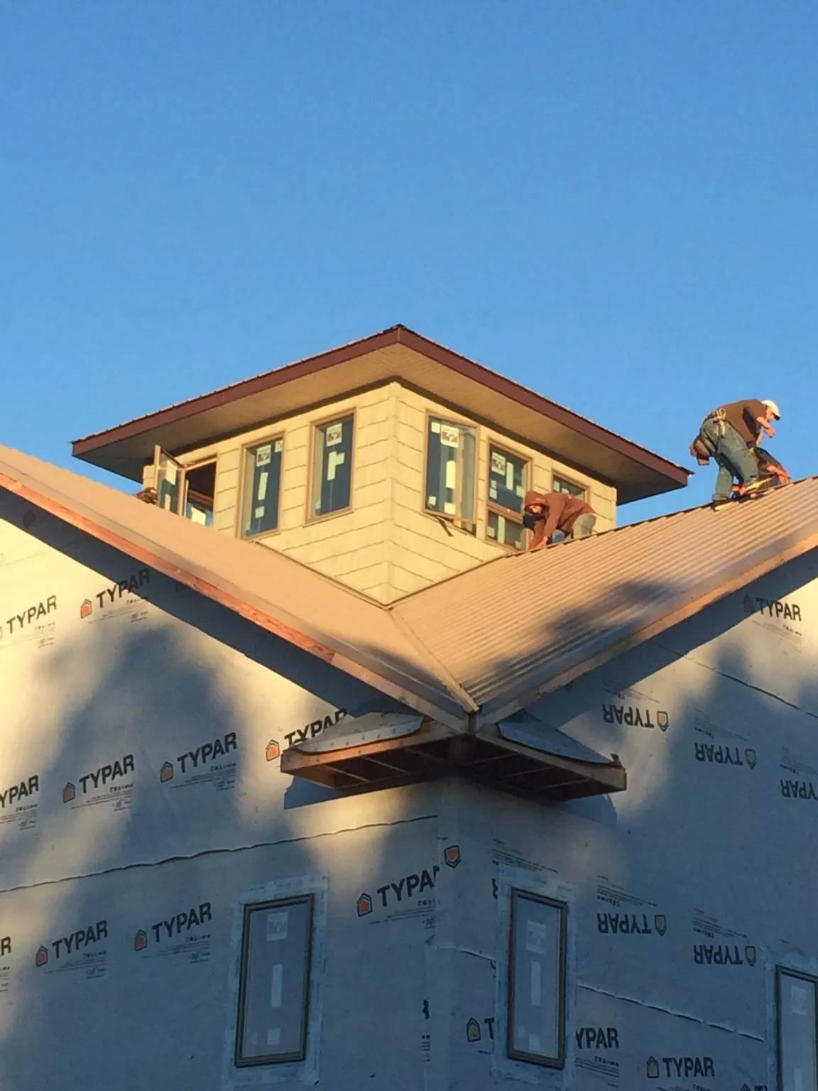 Roofers working around a rooftop cupola on a new metal roof at sunset — Roof Waterproofing in Cropwell by Roofing Brothers